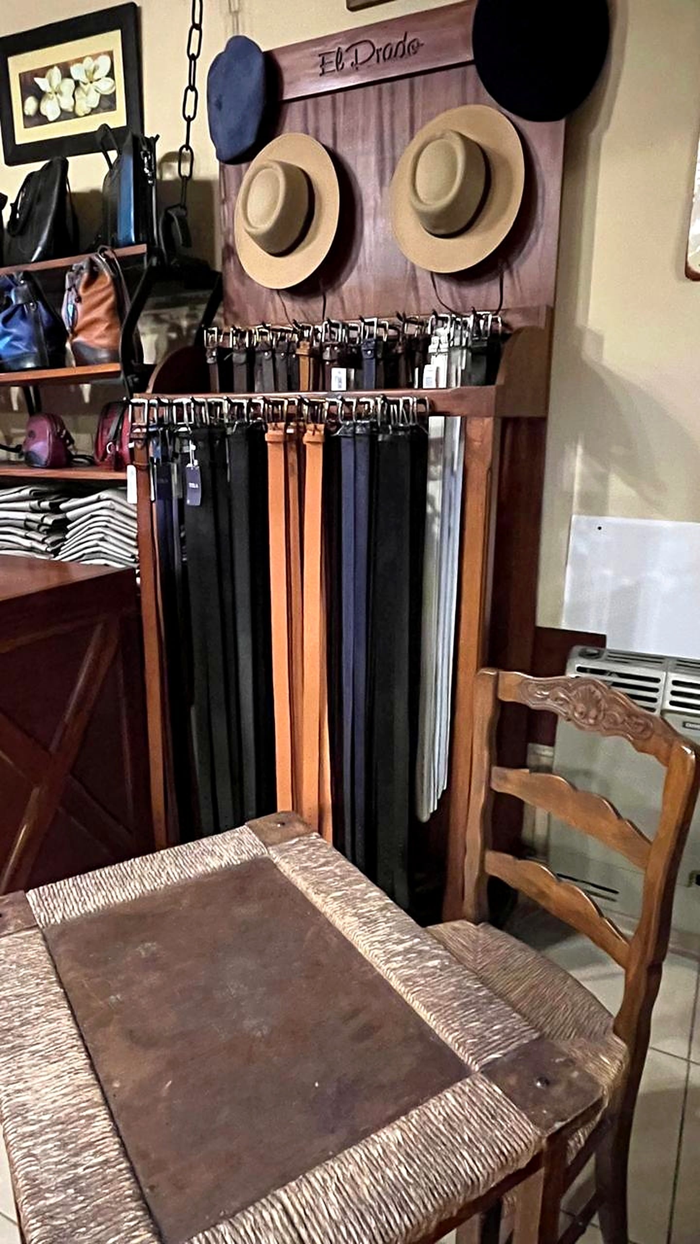 Rincón criollo del local con sombreros de ala, boinas, cinturones de cuero y una silla de paja.