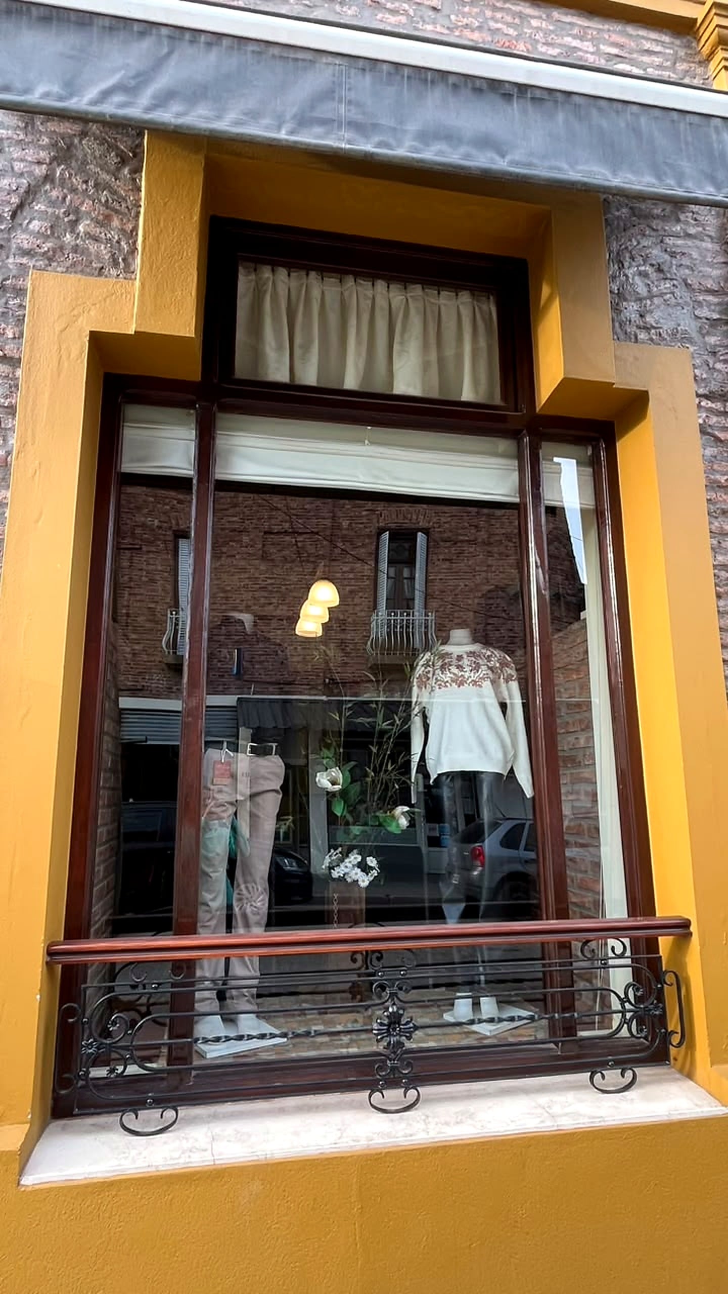 Vidriera de El Prado con ropa de mujer: un pulóver blanco bordado y un pantalón claro en maniquíes.