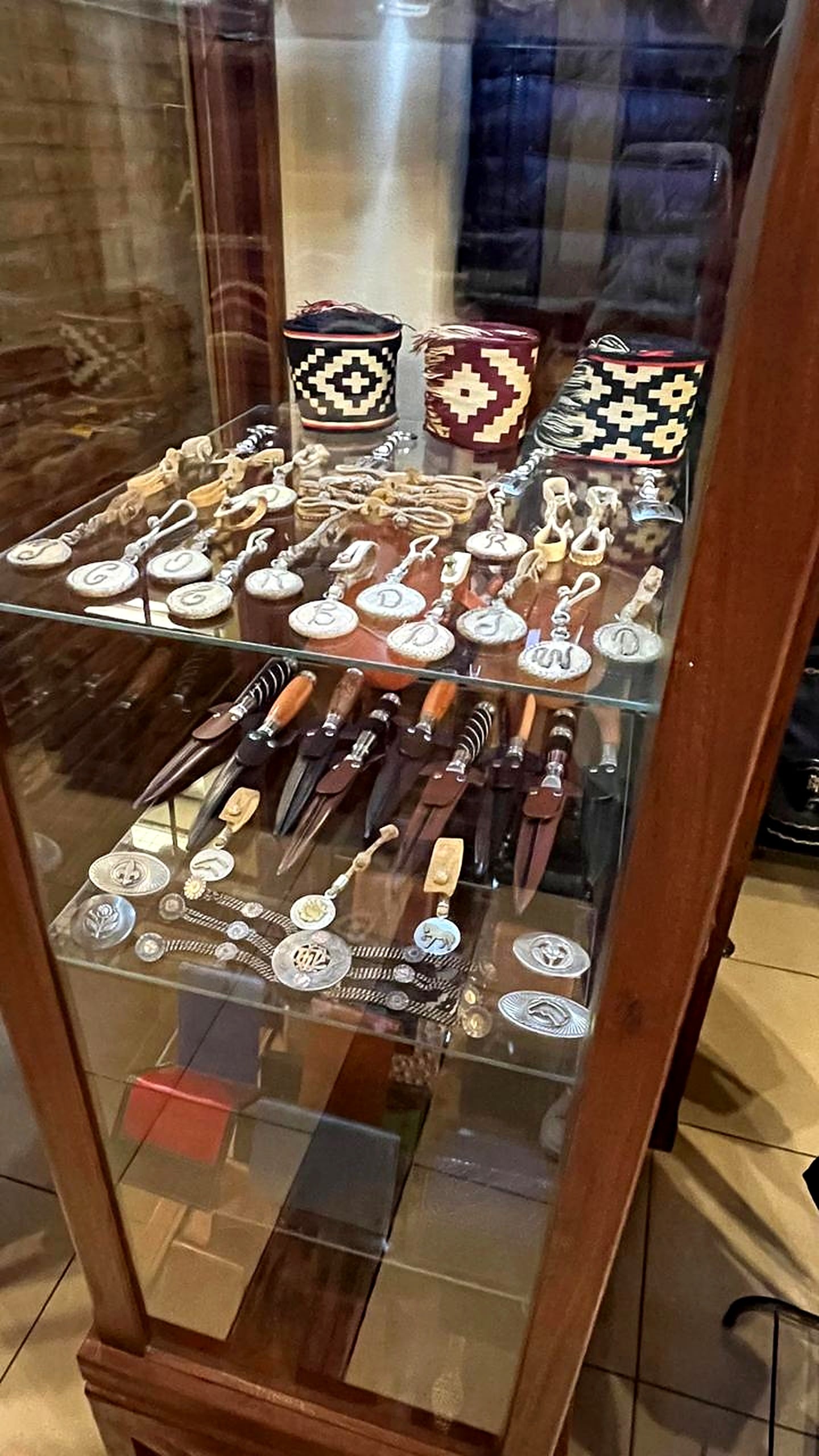 Vitrina de vidrio con cuchillos criollos, llaveros y piezas de platería.